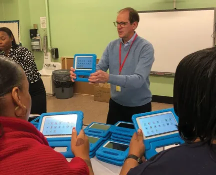 ApSeed founder, Greg Alcorn holds a blue Seedling educational tablet and talks about it to educators